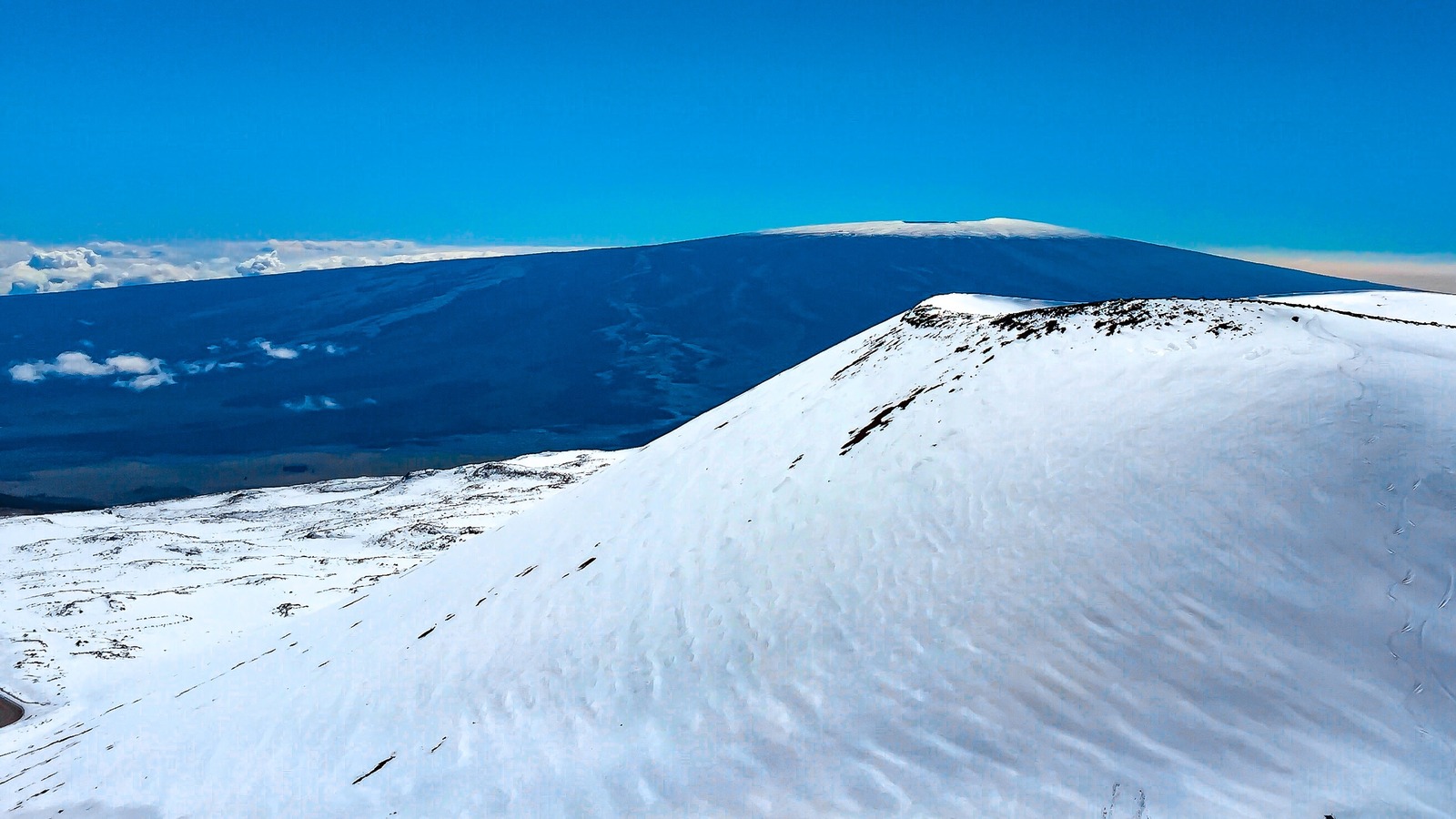 Snow-covered peak of Mauna Kea in Hawaii, showcasing the contrast of snow against the tropical landscape.