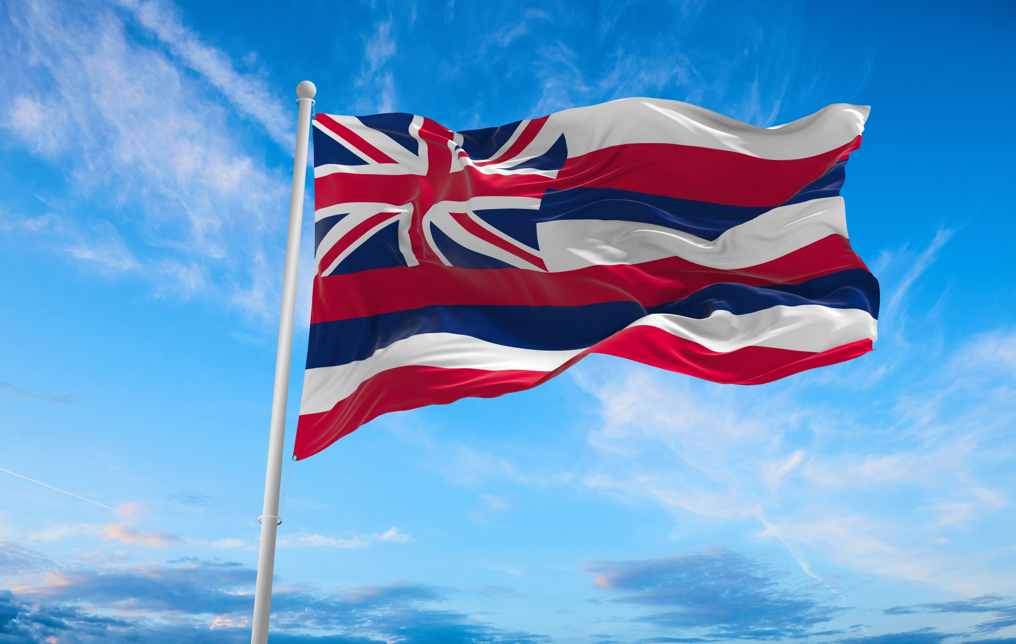 Hawaii State Flag waving proudly against a clear blue sky, showcasing its colors and design.