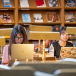 A student using Infinite Campus on a laptop, surrounded by books and school supplies.