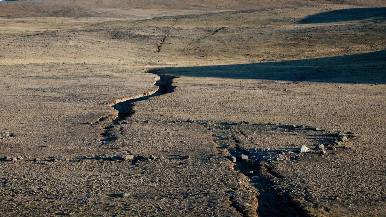 A picturesque view of Hawaii's volcanic landscape with a subtle earthquake warning sign in the foreground