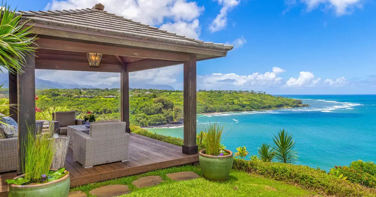 A beautiful beachfront Airbnb in Hawaii with clear blue skies and ocean waves.